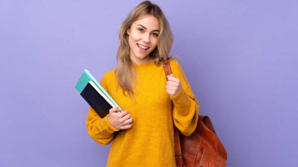 mulher de blusa amarela segurando cadernos e mochila em fundo roxo
