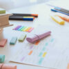mesa com papel, canetas coloridas, marca texto e post it