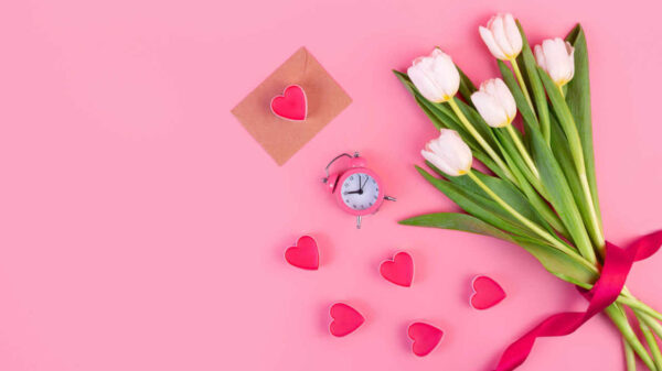 Buquê de tulipas brancas, corações, envelope e um relógio em um fundo rosa pastel isolado. Conceito de "hora do amor", decoração e encontro romântico.