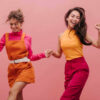 Mulheres jovens dançam e pulando de mãos dadas. Foto profissional de duas melhores amigas se divertindo e rindo alto. Conceito de lazer e estilo de vida.
