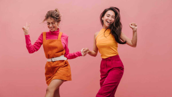 Mulheres jovens dançam e pulando de mãos dadas. Foto profissional de duas melhores amigas se divertindo e rindo alto. Conceito de lazer e estilo de vida.