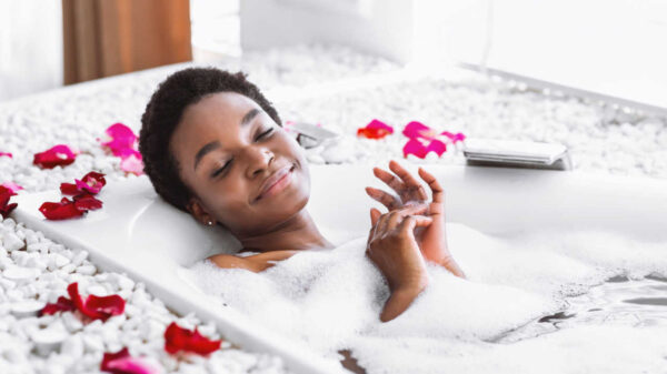 mulher negra num banheira com pétalas de rosas