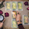 cartas de tarot em uma mesa com uma mão feminina em cima