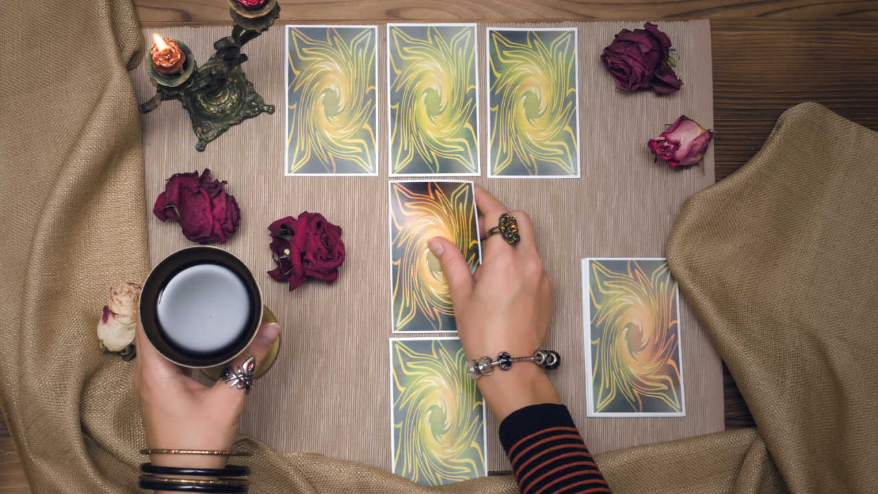 cartas de tarot em uma mesa com uma mão feminina em cima