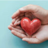 Mãos segurando um coração vermelho. Conceito de cuidados com a saúde e bem-estar.