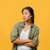 mulher com traços asiáticos olhando para o lado esquerdo em fundo amarelo