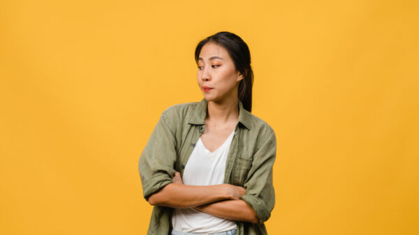 mulher com traços asiáticos olhando para o lado esquerdo em fundo amarelo