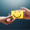 Conceito de experiência do cliente. Cliente dando um feedback com um cartão de rosto sorridente para a mão de um empresário.