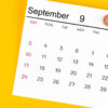 Calendário de setembro de 2023 preso por um alfinete de madeira, sobre um fundo amarelo.
