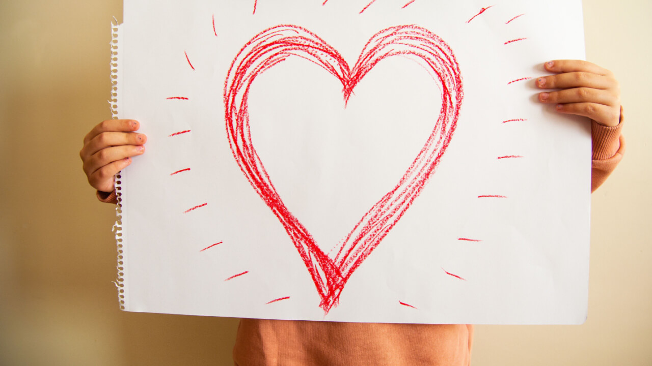 pessoa segurando um grande cartaz branco com um coração vermelho desenhado