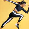 Mulher correndo, sobre um fundo amarelo, usando roupas esportivas. Vista lateral.