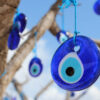 pingentes de olho grego penduradas em uma árvore em um céu azul