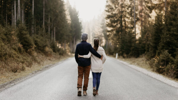 um homem e uma mulher andando abraçados em uma estrada