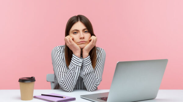 Mulher em um escritório, entediada e sentada, com a cabeça apoiada nas mãos, solitária, decepcionada e cansada Foto de um estúdio interno isolado em um fundo rosa.