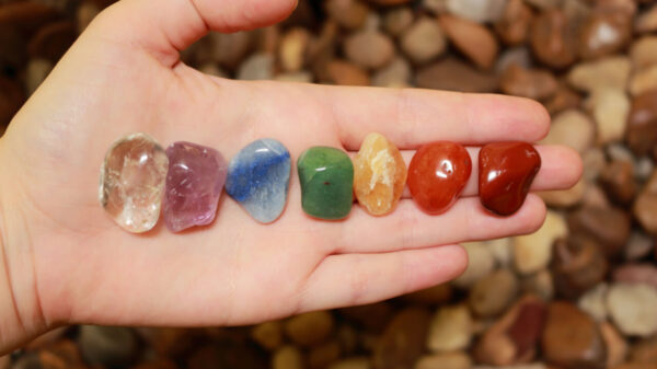 sete pedras dos chakras enfileiradas na palma de uma mão esquerda