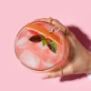 copo com um drink visto de cima em fundo rosa