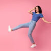 mulher alegre vestindo roupa azul e calça jeans em fundo rosa