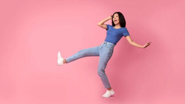 mulher alegre vestindo roupa azul e calça jeans em fundo rosa