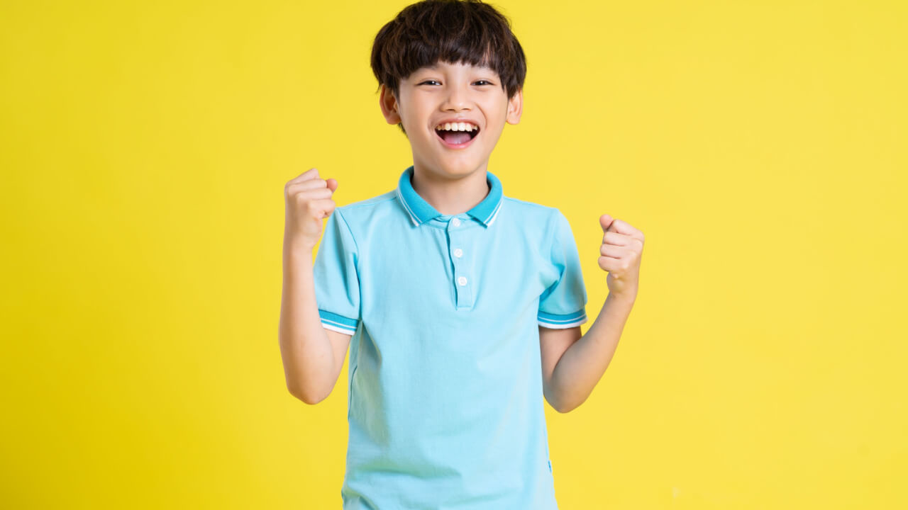 Retrato de um menino posando em um fundo amarelo.