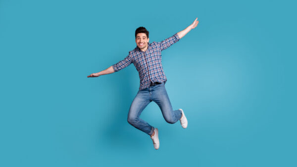 Foto de corpo inteiro de um homem despreocupado, otimista, esticando os braços para os lados, isolado em um fundo azul pastel.