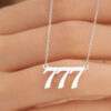 mão feminina segurando um colarzinho com a sequência dos números 777
