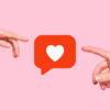 duas mãos tocando o emoji de like das redes sociais