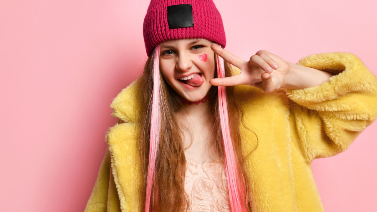 adolescente com uma mecha rosa no cabelo em fundo rosa