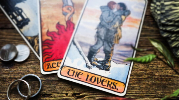 cartas de tarot the lovers em uma mesa de madeira com um par de alianças ao lado esquerda também na mesa