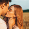 casal hétero se beijando em um campo a céu aberto
