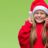 no canto direito da imagem tem uma menina loira de cabelos lisos usando roupa vermelha e chapéu de natal e cruzando os dedos em fundo verde
