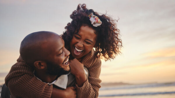 casal feliz se abraçando na praia com o pôr do sol