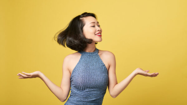 mulher com traços asiáticos sorrindo em fundo amarelo