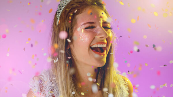 mulher sorrindo com uma tiara na cabeça e confete por cima em findo lilás