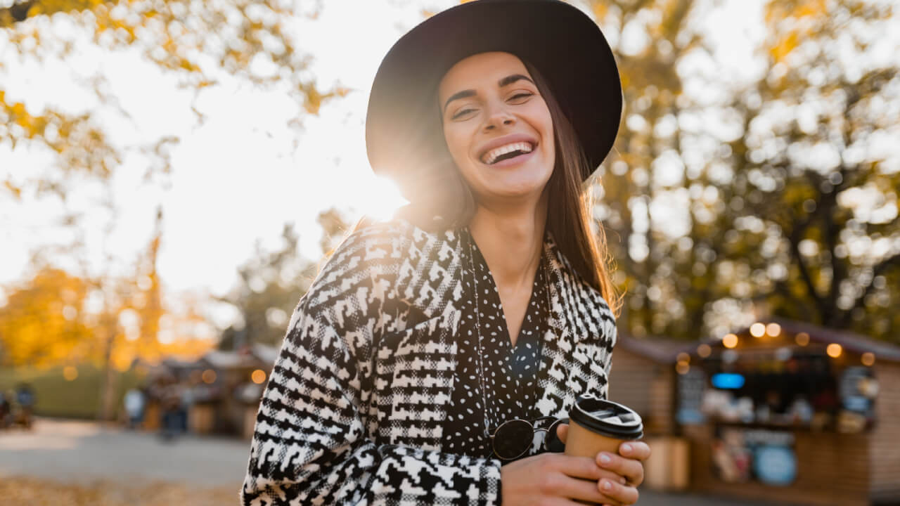 mulher sorrindo em um parque aberto e com o sol forte na fotografia