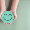 Mãos segurando um sorriso verde feliz em um fundo verde. Conceito de bem-estar.
