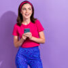 Retrato de uma mulher muito positiva, segurando o celular, isolada em um fundo de cor roxa.