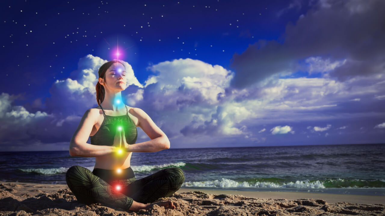 7 chacras. Uma mulher meditando na posição de lótus em um fundo do céu azul escuro e do mar. O conceito de harmonia, cura e calma.