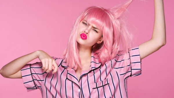 mulher com cabelo, batom e pijama rosa em um fundo também rosa