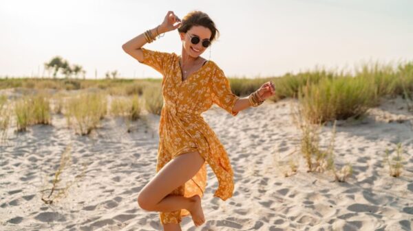 mulher na praia usando vestido amarelo e óculos de sol