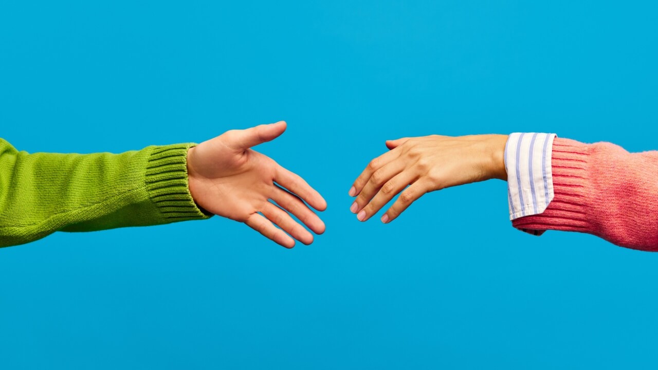 Poster. Duas mãos, uma feminina e uma masculina, estendendo-se uma a outra para um aperto de mão, isoladas em um fundo de cor azul.