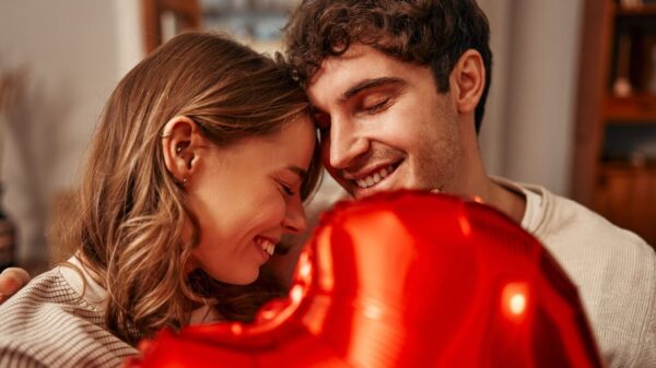 casal abraçado com um balão de coração vermelho na frente