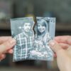 mão segurando uma foto rasgada ao meio que separa um casal