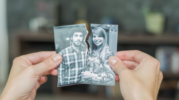 mão segurando uma foto rasgada ao meio que separa um casal