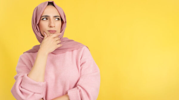 Mulher muçulmana com a mão no rosto e uma expressão pensativa.
