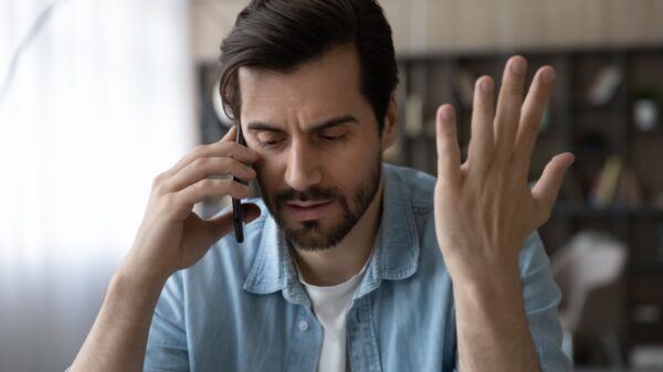 homem falando no telefone com uma cara negativa e a mão esquerda levantada