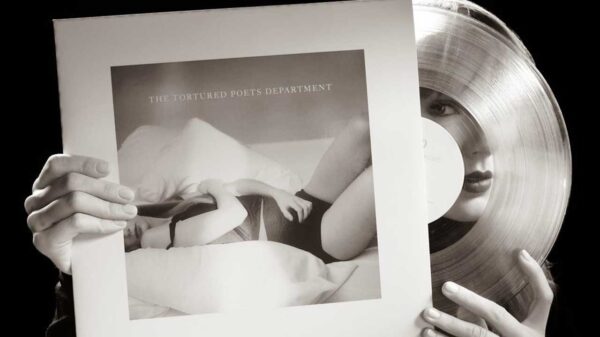 fotografia em preto e branco da cantora taylor swift segurando o disco de vinil do seu álbum the tortured poets department