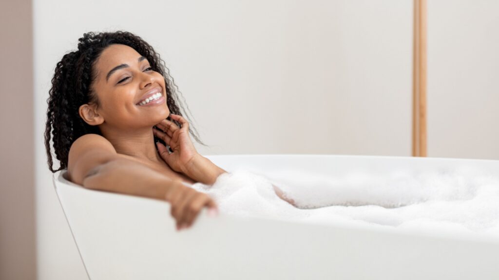 mulher negra em uma banheira coberta por espumas