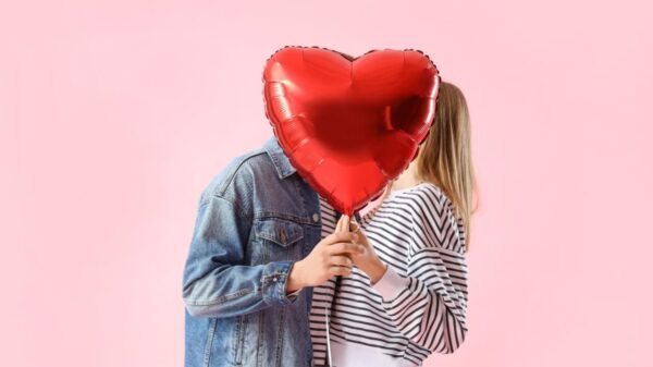 Casal se beijando atrás de balão em forma de coração