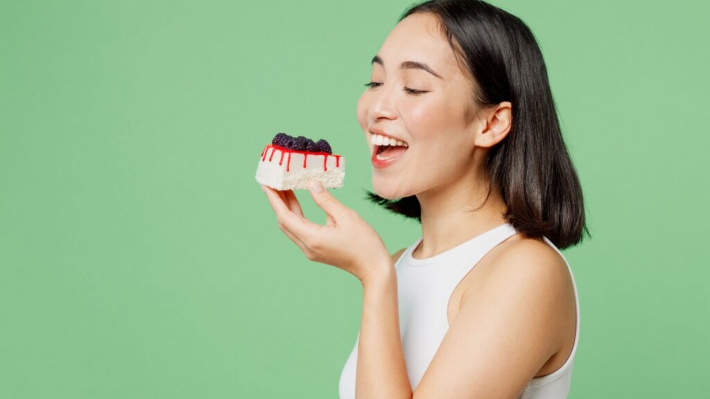 mulher comendo um chesee cake em fundo verde