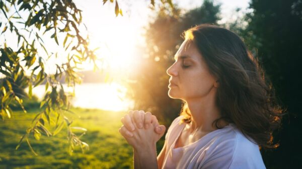 mulher orando em um campo iluminado
